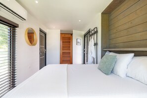 Un dormitorio con una cama grande, un cabecero de madera, un espejo y una ventana con persianas.