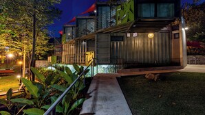 Un bâtiment moderne à plusieurs niveaux, doté d’une terrasse et d’un chemin bien éclairé.