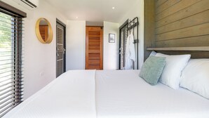 Une chambre à coucher avec un grand lit, une tête de lit en bois, un miroir et une vue sur une porte en bois.