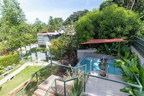 Zona residencial con piscina, terraza de madera y abundante vegetación.