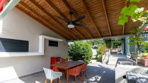 An outdoor patio with a wooden table and chairs, a ceiling fan, and a view of the surrounding garden. - Mata e’ Plátano Guesthouse Suite private pool (Mata de Platano)