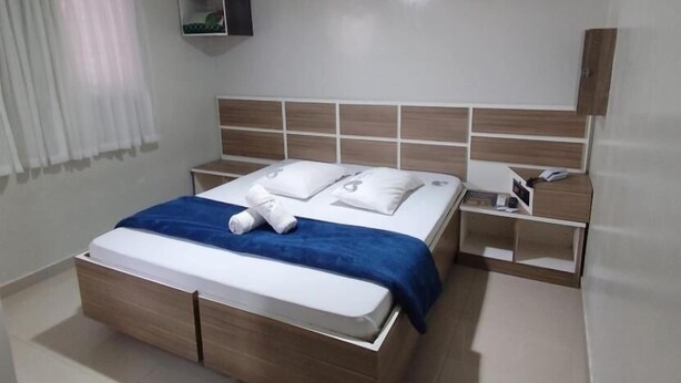 Una camera da letto moderna con un letto in legno, una coperta blu e un comodino con un telefono e un libro.