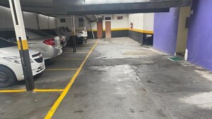 Un parcheggio multipiano con auto parcheggiate sotto una copertura, pavimento in cemento e strisce gialle che delimitano i posti auto.