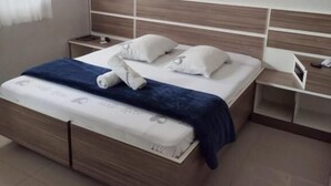 Camera da letto moderna con un letto in legno, biancheria da letto bianca, una lampada a sospensione rossa e un comodino a parete.