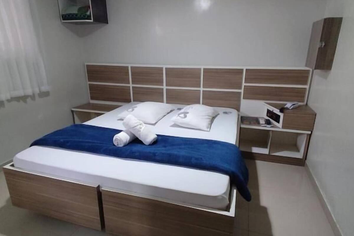 Un dormitorio moderno con una cama de madera, una manta azul y una mesita de noche con una lámpara.