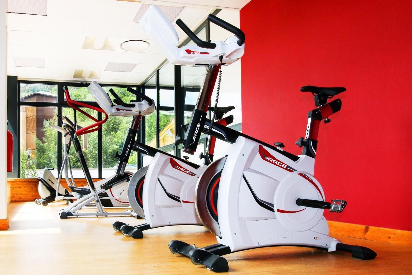 Un gimnasio con bicicletas estáticas, cinta de correr y máquina de remo.