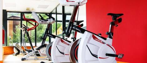 Un gimnasio con bicicletas estáticas, cinta de correr y máquina de remo.