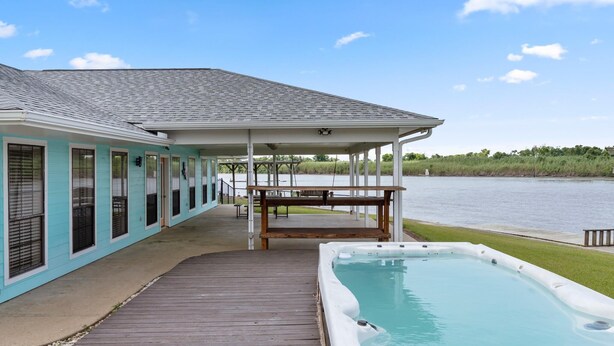 A house with a covered patio, a hot tub, and a view of a lake. - Matagorda-Stunning Waterfront Views-Swim Spa-Private Pier-Relax (Matagorda)