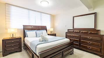 A bedroom with a large bed, a dresser, a mirror, and two bedside tables.