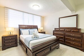 Um quarto com uma cama grande, uma cômoda, um espelho e duas mesas de cabeceira.