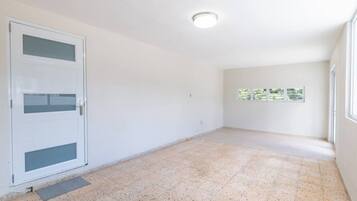 Een kamer met betegelde vloer, een deur met geëtste glaspanelen en een plafondlamp.