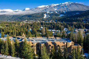 A residential area with houses surrounded by dense forests and a mountain range in the background. - The Bear Den: 2BR - Pool, Hot Tub, Free Parking (Whistler)
