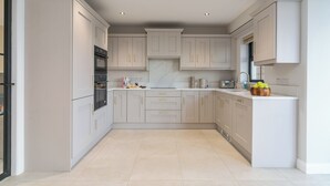 A modern kitchen with white cabinets, a marble countertop, and a built-in oven. - Modern Entire Home Retreat in Newry (Newry)