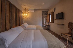 A bedroom with two beds, a television, and a wooden chair. - Hotel C. Andreu  (San Miguel de Allende)