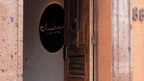 A hotel entrance with a wooden door, a circular sign with the hotel's name, and a number plaque. - Hotel C. Andreu  (San Miguel de Allende)