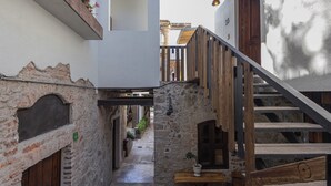 A narrow stone corridor with a wooden staircase on one side and a white wall on the other. - Hotel C. Andreu  (San Miguel de Allende)