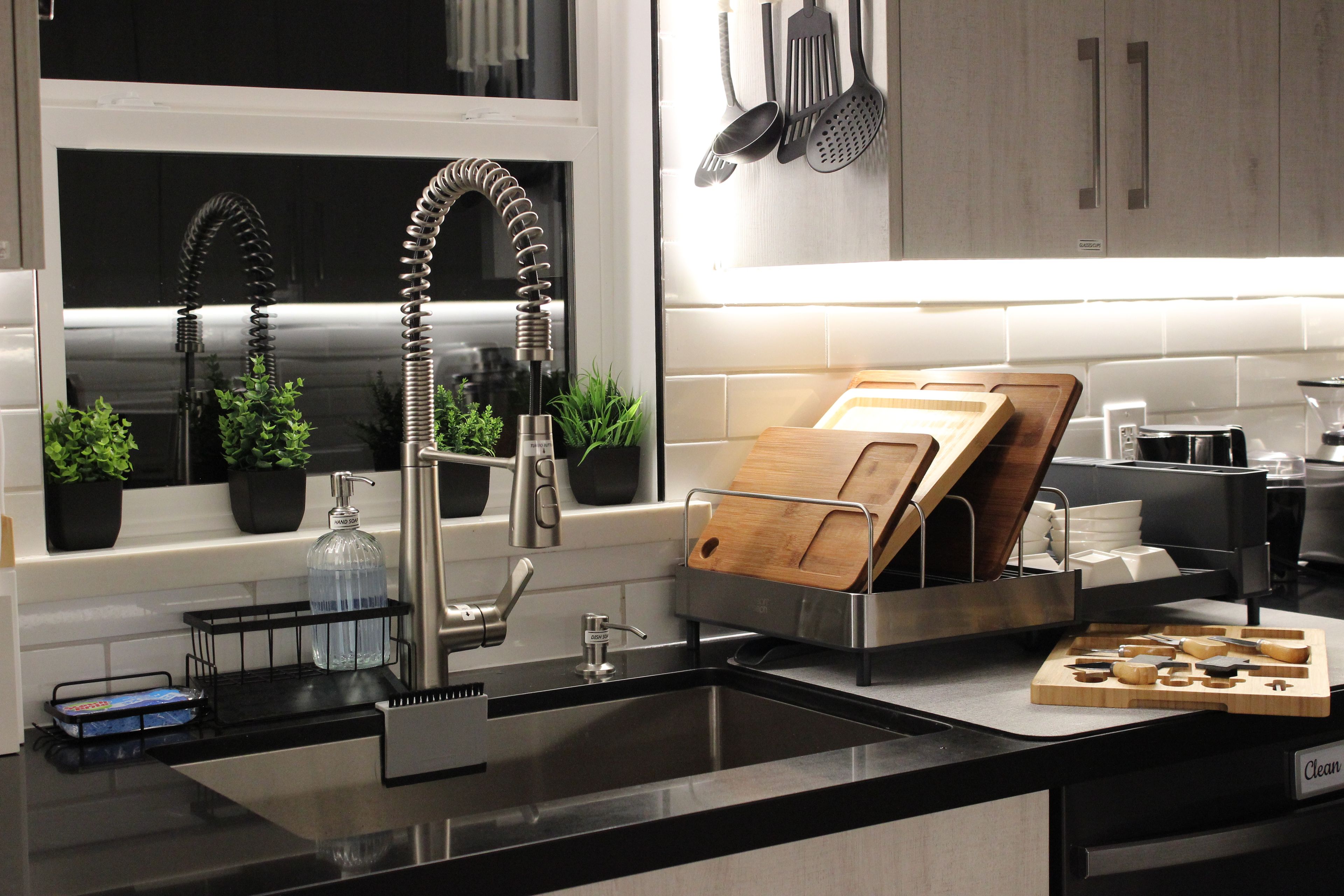Una cucina moderna con lavello in acciaio inox, portatovaglioli in legno e scolapiatti.