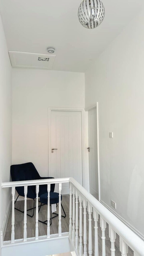 A staircase with white balusters leading to a landing. A black chair is placed on the landing.