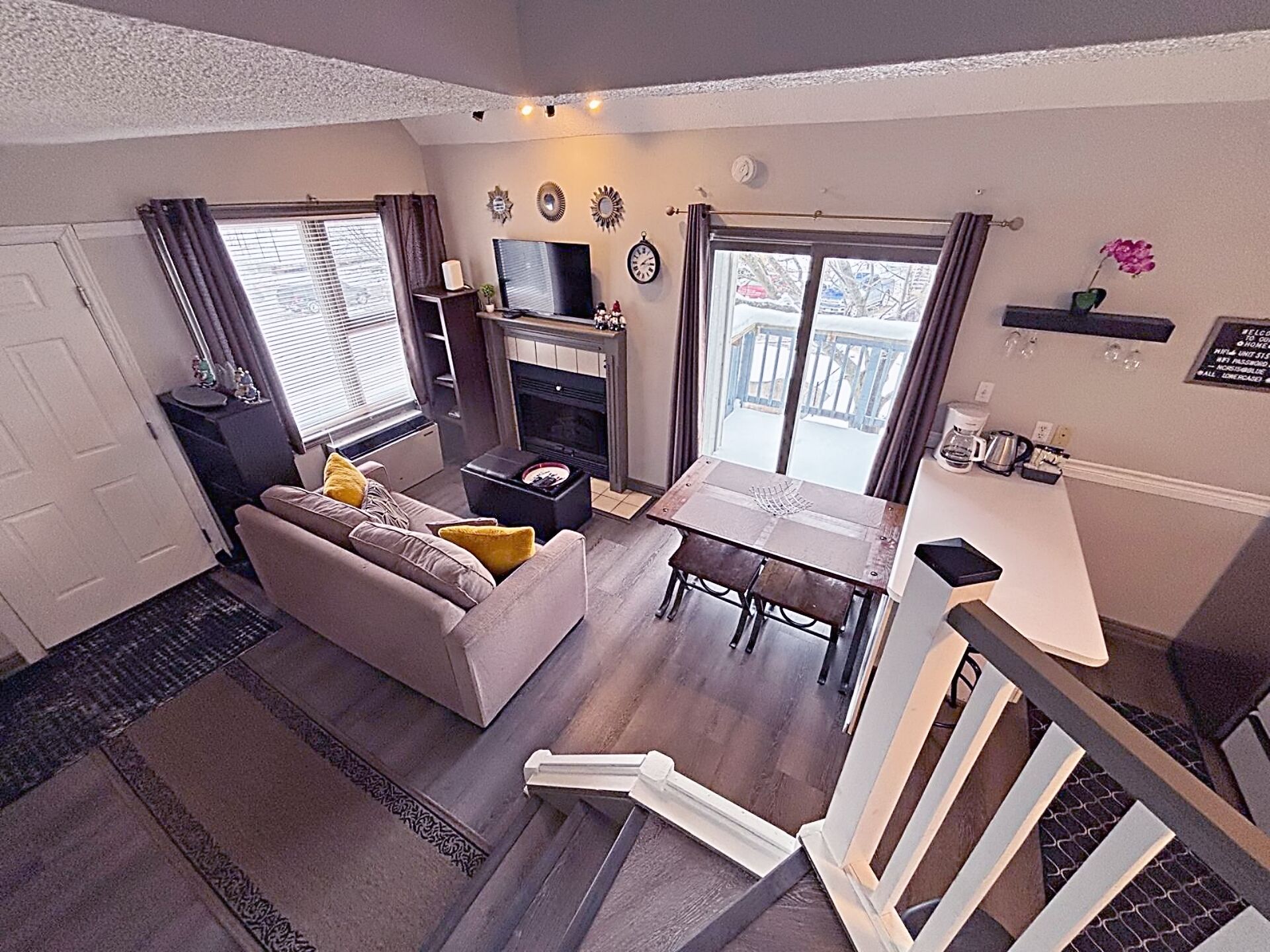 Een knus woongedeelte met een bank, een klein tafeltje, een open haard en een balkon met uitzicht.