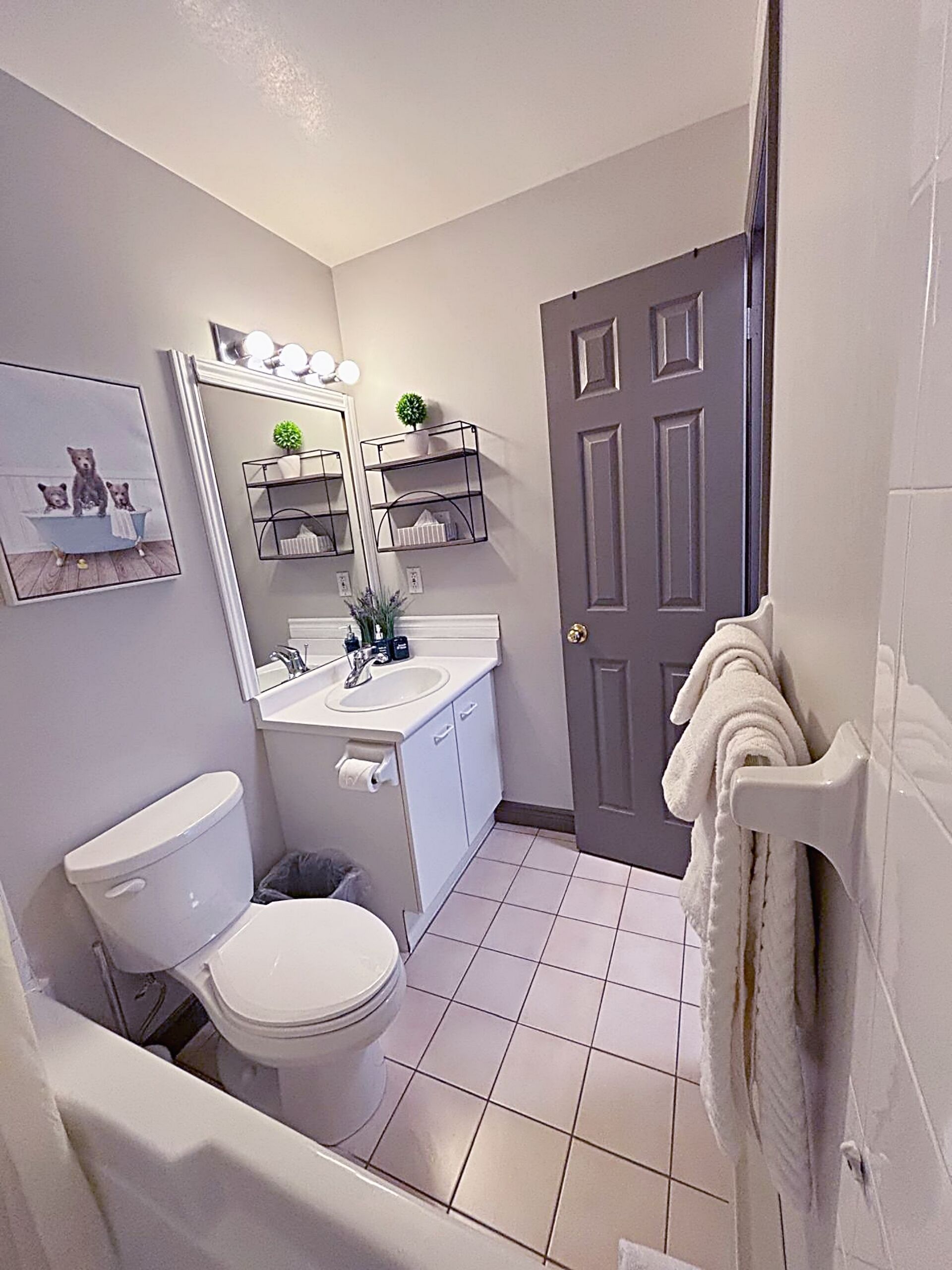 A bathroom with a toilet, sink, mirror, and towel rack.
