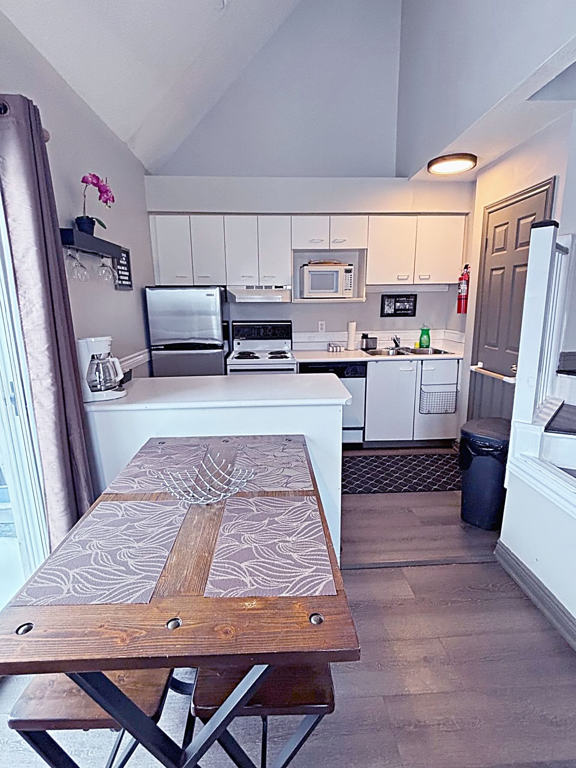 Una cocina compacta con gabinetes blancos, microondas, estufa y refrigerador.