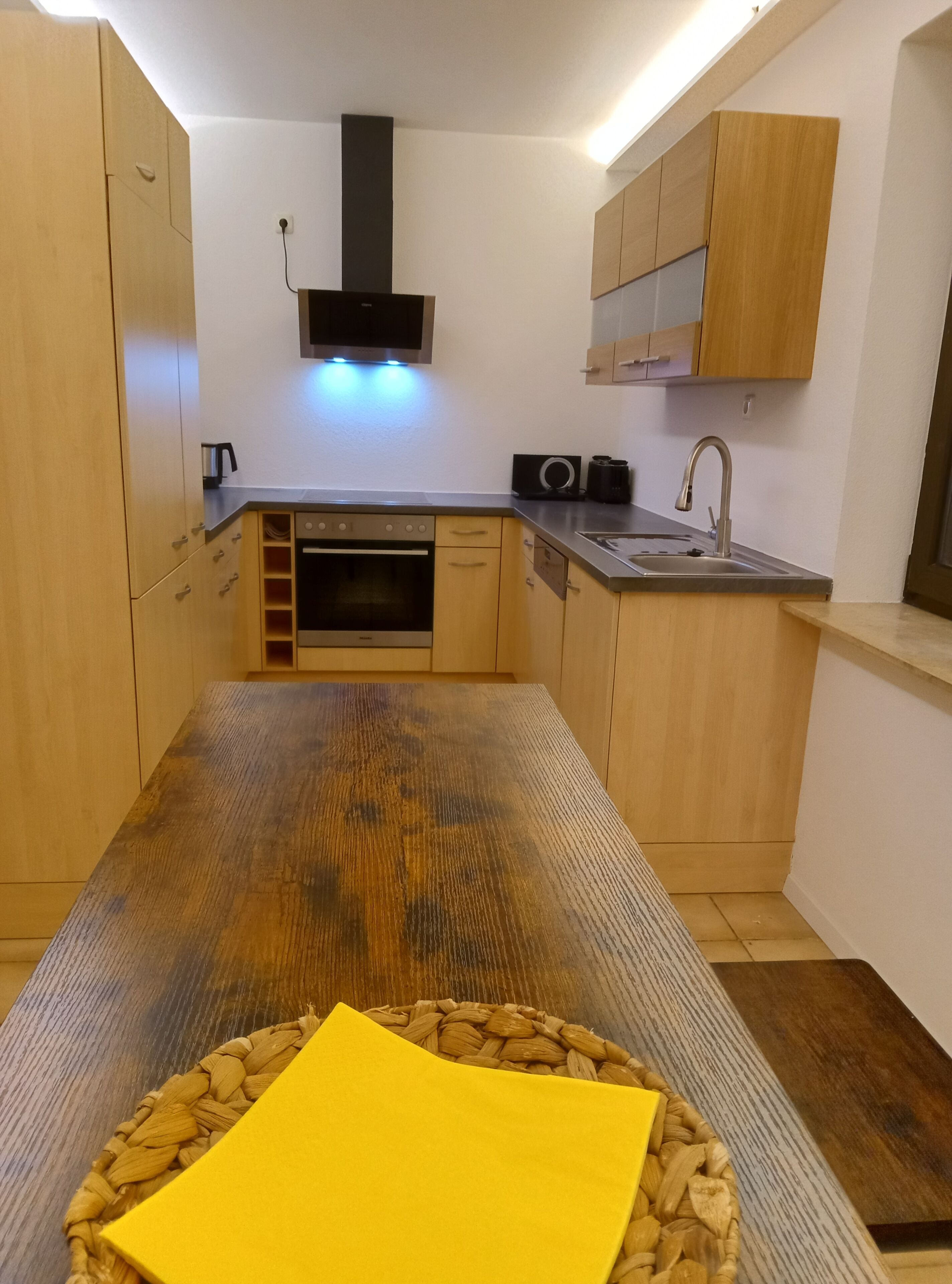 Eine kompakte Küche mit Holzausstattung, einem eingebauten Ofen und einer Edelstahl-Spüle.