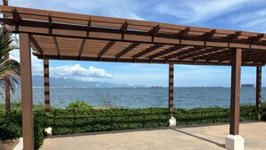 Zona exterior coberta amb vistes al mar, sòl de formigó i vegetació.