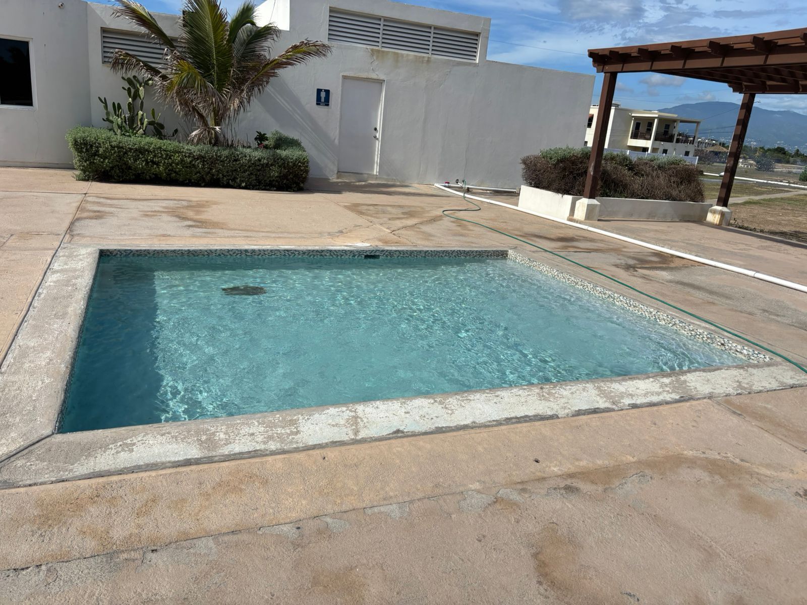 Ein rechteckiger Pool mit klarem, blauem Wasser, umgeben von einer Betonplattform.