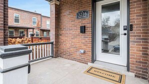 A brick exterior with a white door and a welcome mat.