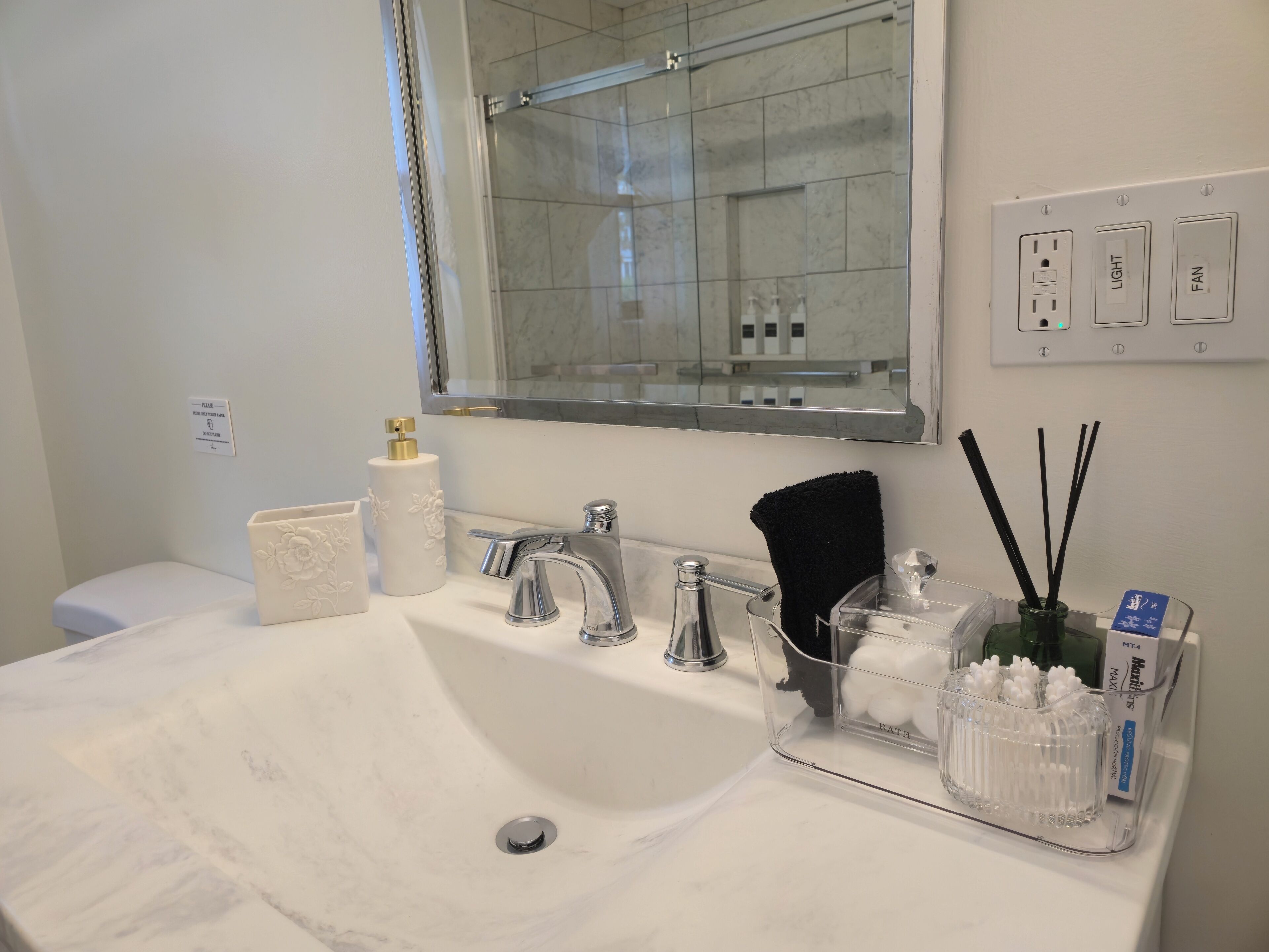 Un baño con lavamanos blanco, un espejo, inodoro y zona de ducha.