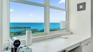 Ein modernes Hotelzimmer mit großem Fenster und Blick auf das Meer und den Hafen.