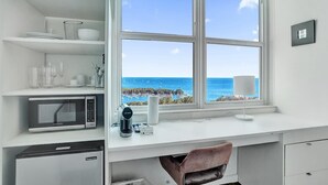 Eine moderne Küche mit Meerblick, einer Mikrowelle, einer Kaffeemaschine und einem Kühlschrank.
