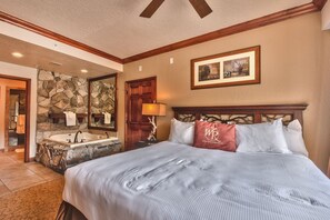 Ein Schlafzimmer mit einem großen Bett, einer Steinsäule, einer Badewanne und einem hölzernen Kopfteil.