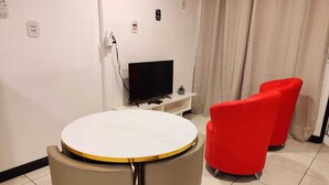 Une pièce avec une table ronde, deux chaises, un téléviseur à écran plat et un fauteuil rouge.