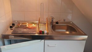 Pieni, käytännöllinen keittiö, jossa on pesuallas, liesi ja jääkaappi.