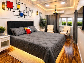 A bedroom with a large bed, bedside tables, a potted plant, a chair, and a window with curtains. - Modern 2BR King Suite • 5 Min to Baby Beach • Fast WiFi • Sleeps 4 (Ceru Colorado)