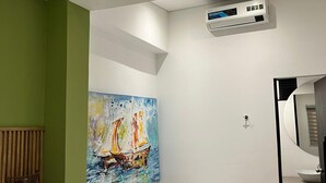 A modern bathroom with a freestanding bathtub, a painting of a sailboat, and a green accent wall. - Hotel Gallery Boutique (Pereira)