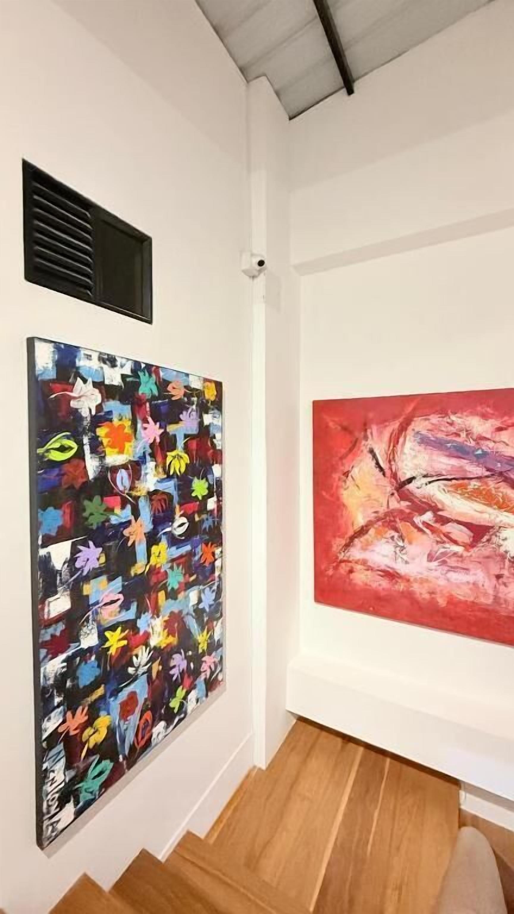 Une galerie d’art où l’on peut admirer deux grandes peintures accrochées à des murs blancs.