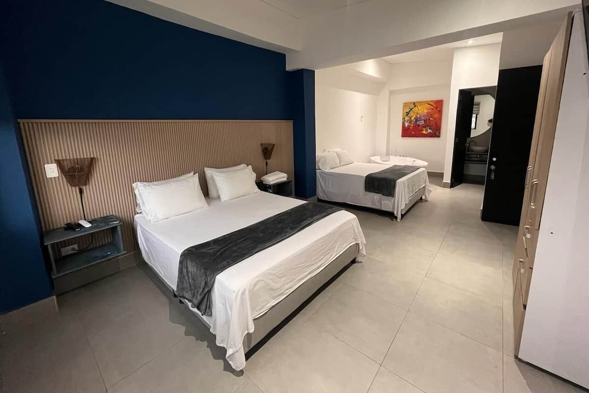 A hotel room with a large bed, a smaller bed, a desk, and a chair.