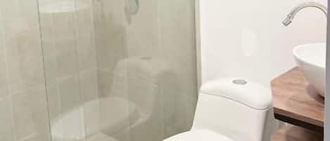 Une salle de bain moderne avec une douche à parois de verre, des toilettes blanches et un meuble-lavabo en bois avec un évier.