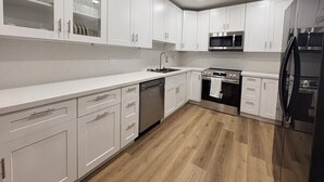 Eine moderne Küche mit weißen Schränken, Edelstahlgeräten und Holzboden.
