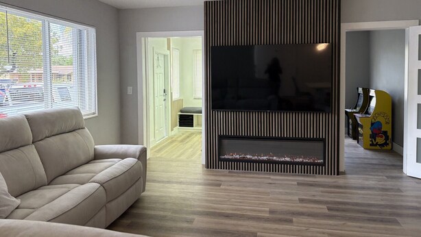 Ein modernes Wohnzimmer mit einer Couch, einem großen Flachbildfernseher und einer Wand als Holzakzent.