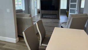 Ein modernes Wohnzimmer mit Flachbildfernseher, beigefarbenen Sofas und einem Esstisch.