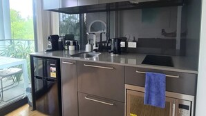 Eine moderne Küche mit dunklen Schränken, einem eingebauten Backofen und einer Kaffeemaschine.