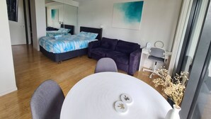 Ein modernes Schlafzimmer mit Bett, Sofa, einem kleinen Tisch und einem Sessel.