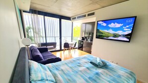 Ein modernes Hotelzimmer mit einem großen Bett, einem Fernseher, einer Couch und einem Essbereich.