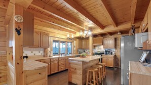 Una cocina de estilo rústico con muebles de madera, una isla central y un refrigerador grande.