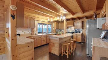 Une cuisine de style rustique, avec des éléments en bois, comprenant un îlot central, des armoires en bois et un grand réfrigérateur.