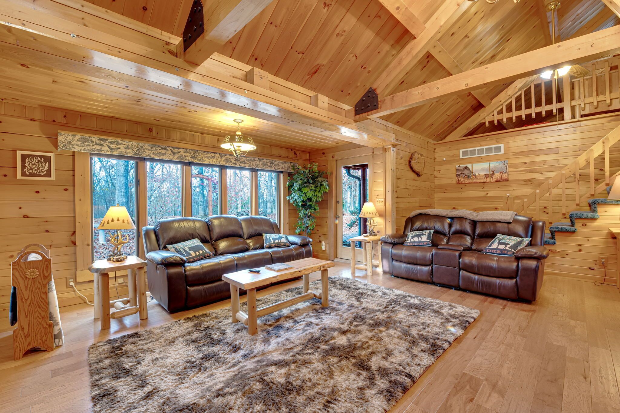 L’intérieur d’un chalet confortable, avec deux canapés en cuir, une table basse en bois et une grande peau de bête servant de tapis.