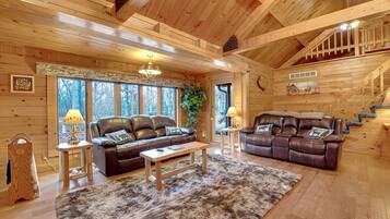 L’intérieur d’un chalet confortable, avec deux canapés en cuir, une table basse en bois et une grande peau de bête servant de tapis.